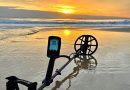 détecteur de métaux Manticore de Minelab posé sur du sable mouillé à la plage avec du sable noir