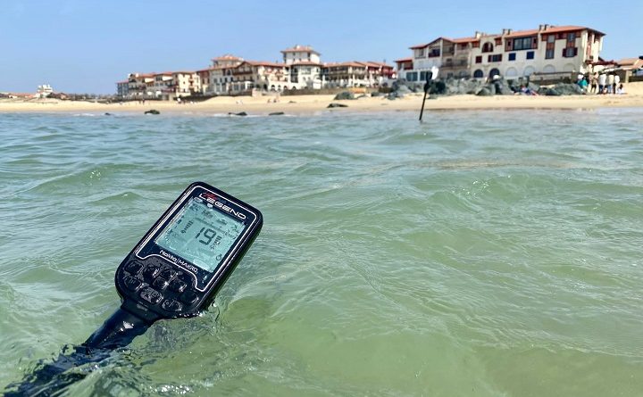 prospecteur avec son detecteur de métaux Nokta Legend au bord de la mer au milieu des vague plage de Capbreton