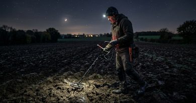 Un prospecteur dans un champ avec son détecteur de métaux, au milieu de la nuit